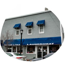A picture of the front of a laundromat with snow coming down